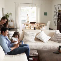 Family of four sitting on couch looking at a tablet